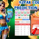 Promotional image for the 92PAK Color Prediction Game featuring a vibrant female character in a blue outfit holding a smartphone, a game interface showing color and number predictions, and a winning screen with a bonus amount of ₹98,000. The BasantClub logo is also visible.